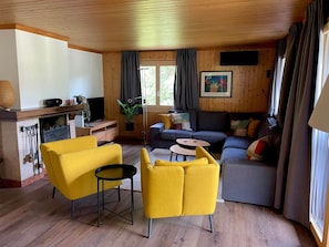Una sala de estar acogedora con chimenea, un sofá, un sillón amarillo y una mesita de centro.