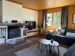 A cozy living room with a fireplace, a television, a sofa, and a dining table.