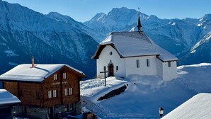Ein verschneites Bergdorf mit Kirche und einem Holzbau.