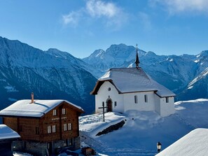 Un village de montagne enneigé, avec une église et un bâtiment en bois.