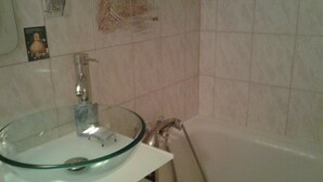 A bathroom with a glass bowl sink, a handheld showerhead, and a tiled wall. - SINGLE ROOM (Nanterre)