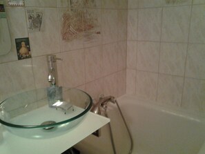 A bathroom with a glass bowl sink, a handheld showerhead, and a tiled wall. - SINGLE ROOM (Nanterre)