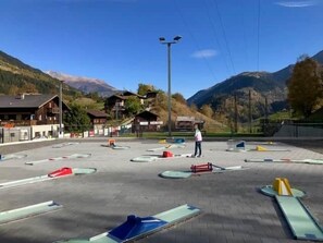Ein Skigebiet im Freien mit einer Person, umgeben von Skiausrüstung und Gebäuden im Hintergrund.