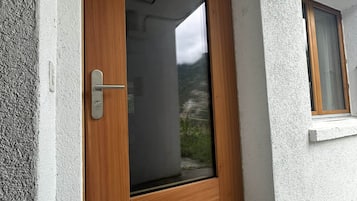 Eine Holztür mit Fensterglas, einem Metallgriff und einem kleinen Fenster zur rechten Seite.