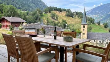 Ein Essbereich im Freien mit Tisch, Stühlen, einer Flasche und einer Schüssel.