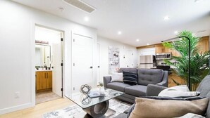 Una sala moderna con un sofá, una mesa de centro y una cocina con armarios y electrodomésticos.