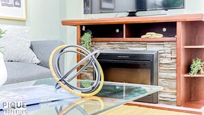 Una sala de estar con chimenea, televisor montado encima y un sofá.