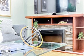 Un salon avec une cheminée, un téléviseur fixé au-dessus et un canapé.