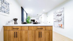 Una cocina moderna con armarios de madera, una cafetera y un cuadro abstracto grande en la pared.