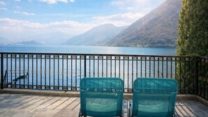 Ein Balkon mit Blick auf einen See und Berge, zwei Stühle und ein Geländer.