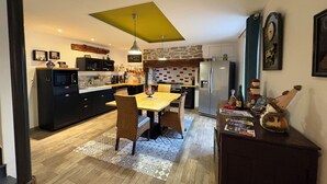 Een moderne keuken met een eethoek, met een groot kookeiland, inbouwapparatuur en een bijzonder plafondontwerp.