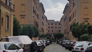 Una calle empedrada flanqueada por coches aparcados y edificios de varios pisos.