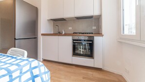 Cocina compacta con horno integrado, refrigerador de acero inoxidable y ventana que proporciona luz natural.