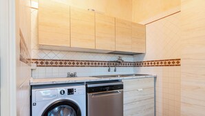Une cuisine compacte avec des meubles en bois, un pare-feu en carrelage, un lave-vaisselle intégré et un lave-linge.