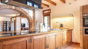 Une cuisine dotée d’un grand îlot central, de meubles en bois, d’une arche en briques et d’un dosseret carrelé.
