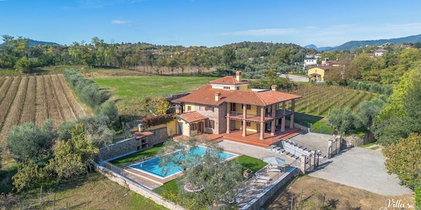 A large villa with a swimming pool, a covered patio, and a view of the surrounding countryside.
