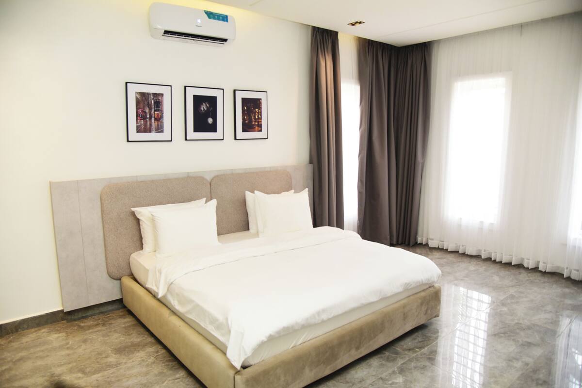 Une chambre d’hôtel avec un lit, un appareil de climatisation et trois tableaux encadrés accrochés au mur.