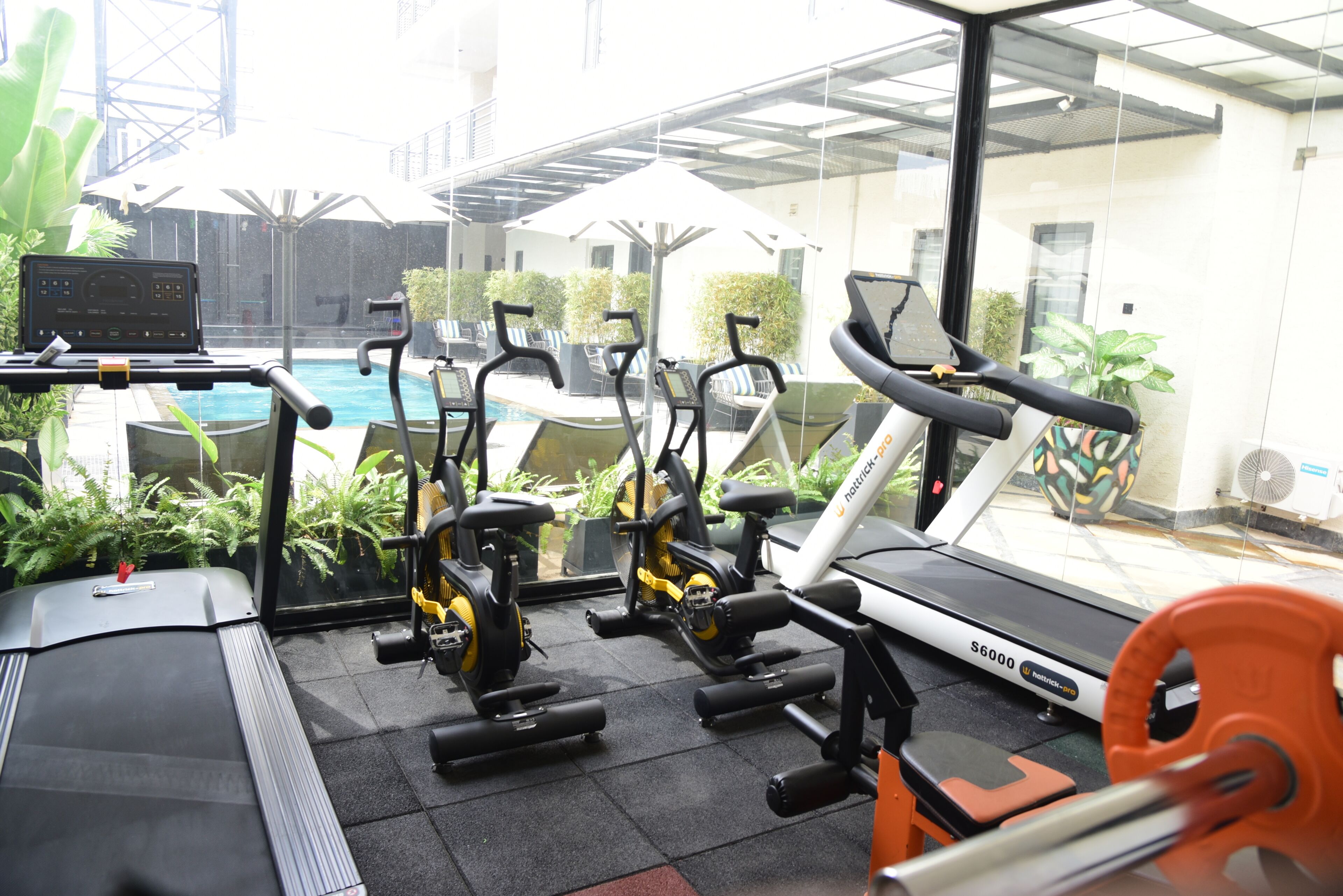 Un gimnasio con equipamiento de ejercicio, cinta de correr y piscina.