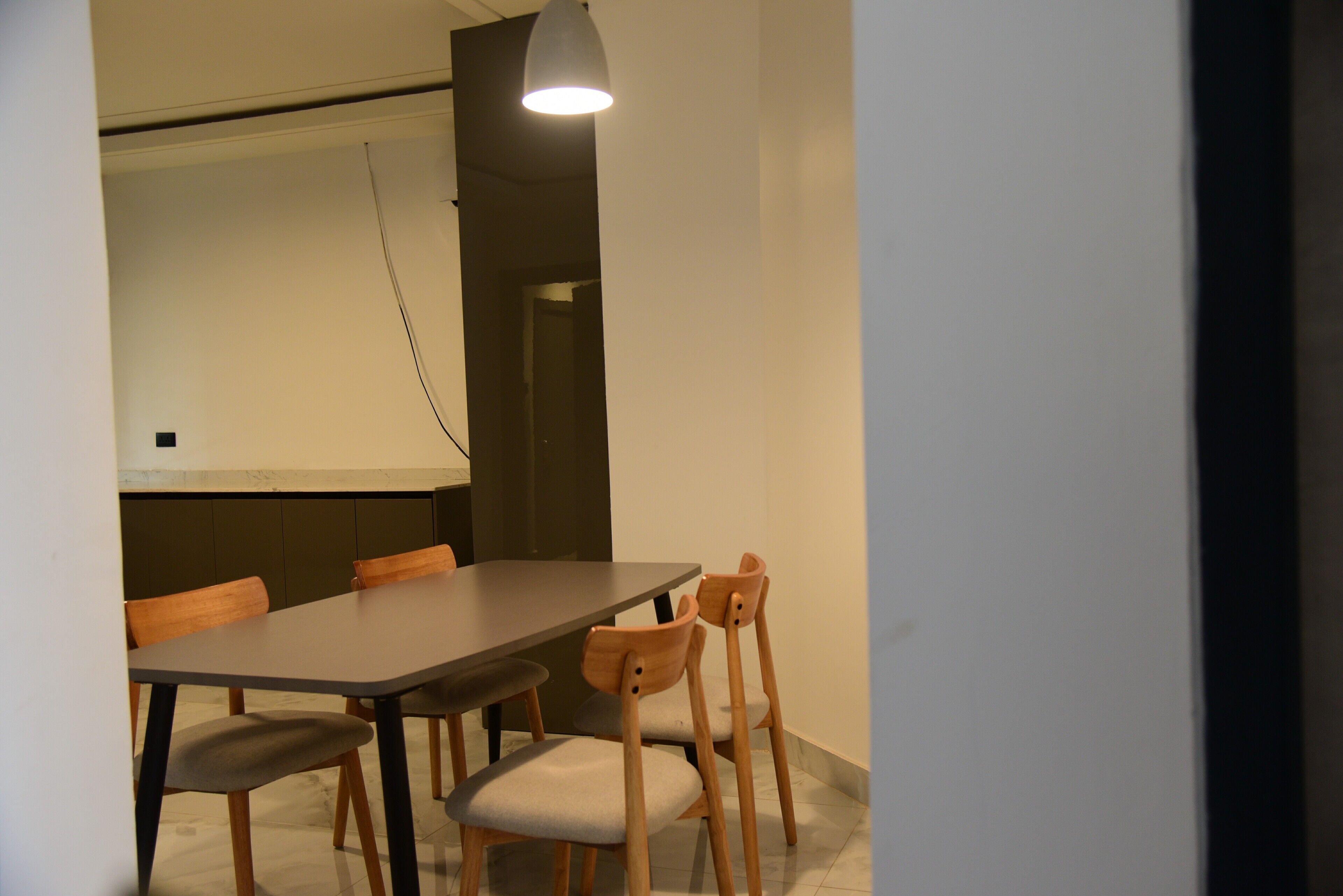Et mødelokale med et langt bord, seks stole, et projektorskærm og en hængende lampe.