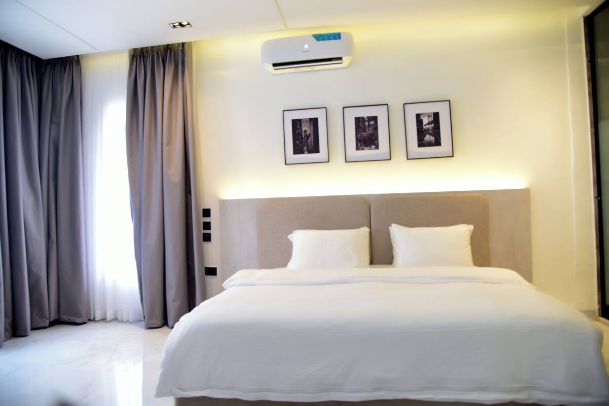 Une chambre d’hôtel avec un grand lit, un appareil de climatisation et trois tableaux encadrés accrochés au mur.