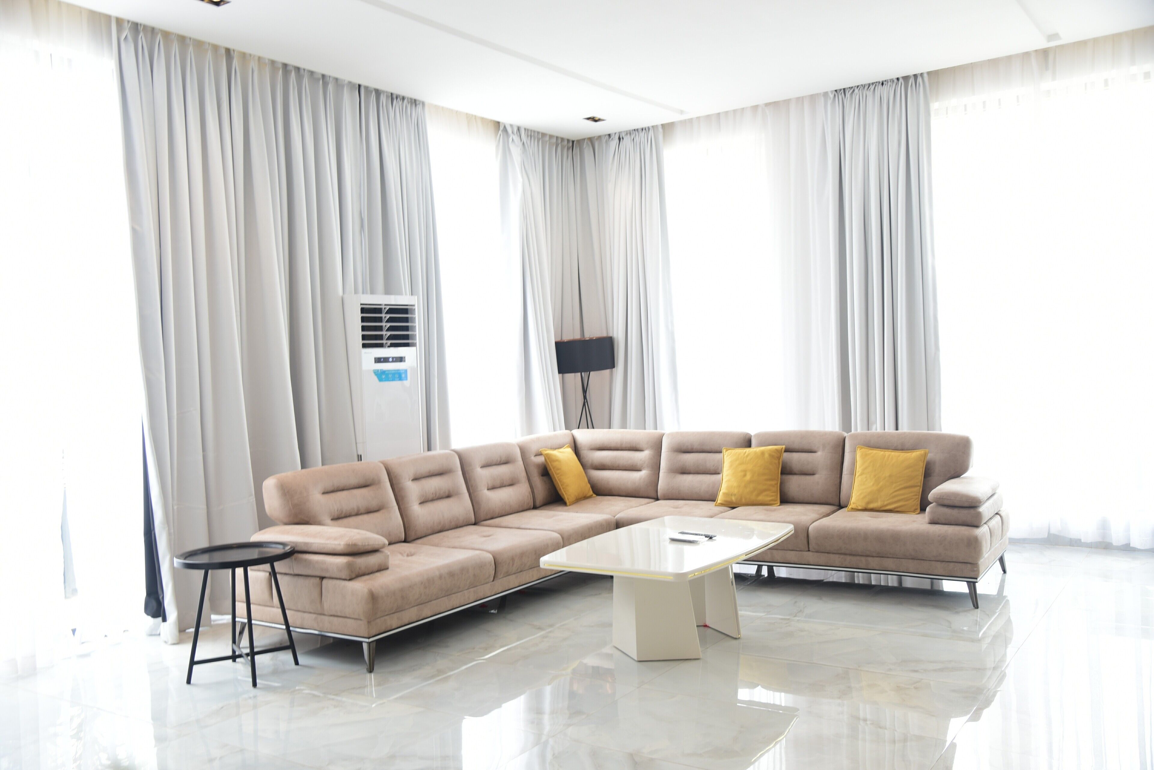 Un salon moderne avec un canapé d’angle, une petite table et un lampadaire.
