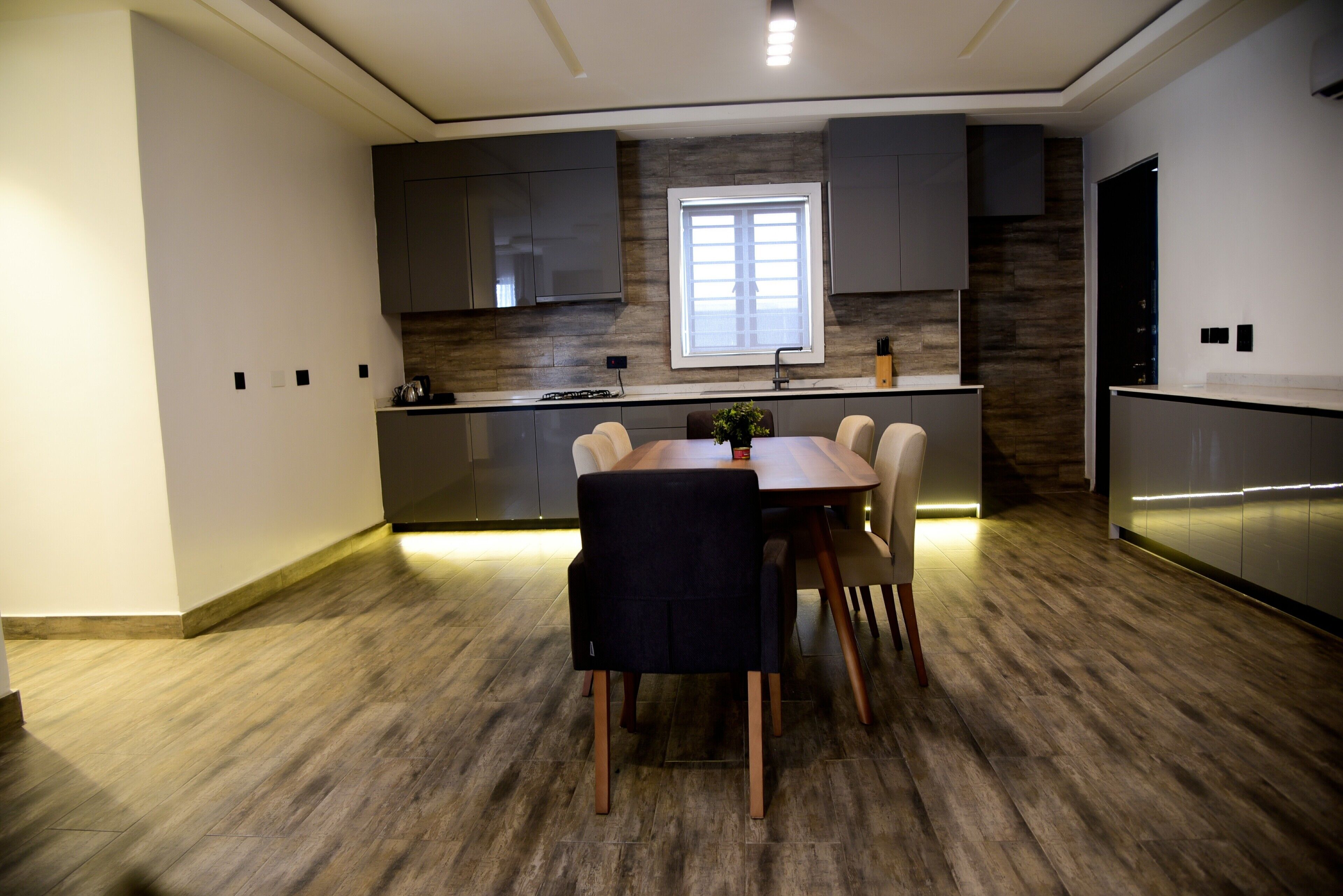 A modern kitchen with a dining area, wooden flooring, and built-in cabinets.
