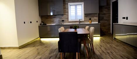 A modern kitchen with a dining area, wooden flooring, and built-in cabinets.