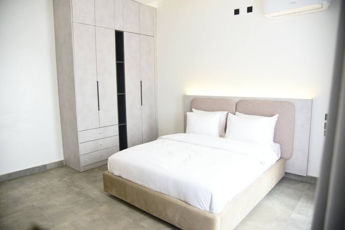 Une chambre à coucher comprenant un lit, une armoire et un climatiseur fixé au mur.