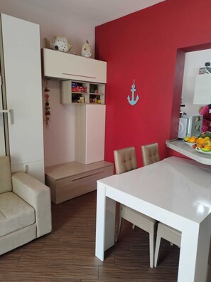 Ein modernes Wohnzimmer mit einem weißen Sofa, einem Esstisch und einer roten Akzentwand.