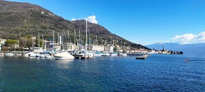 A marina with boats docked, a mountainous backdrop, and a clear sky. - Apartment in Salò, just a stone's throw from the center (Salò)