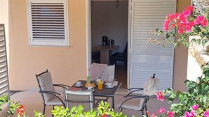An outdoor seating area with a table, chairs, and a view into the house. - A1 - Chic One-Bedroom Apartment with Parking and Garden view (Slano)
