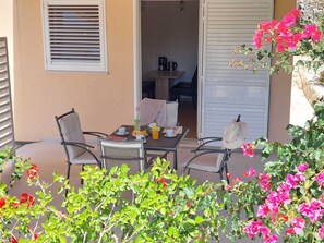 An outdoor seating area with a table, chairs, and a view into the house. - A1 - Chic One-Bedroom Apartment with Parking and Garden view (Slano)