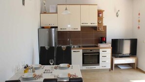 A modern kitchen with a dining area, a TV, and a built-in oven. - A1 - Chic One-Bedroom Apartment with Parking and Garden view (Slano)