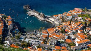 An aerial view of a coastal town with a lighthouse, marina, and terraced houses. - Studio apartment with patio in Câmara de Lobos | Privileged location (Câmara de Lobos)