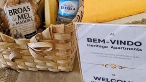 A welcome sign for Heritage Apartments, a wicker basket with bread, bananas, and a water bottle. - Studio apartment with patio in Câmara de Lobos | Privileged location (Câmara de Lobos)