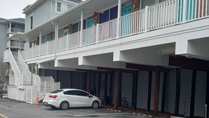 En byggnad med flera våningar, framför vilken en vit bil är parkerad.
