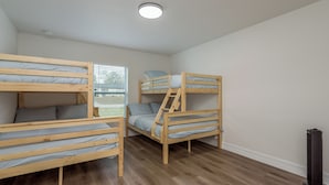 A room with two bunk beds, a window with blinds, a standing heater, and a white ceiling.