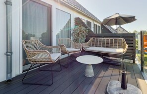 A deck with wicker furniture, a round table, and a large umbrella. - Holiday apartment Mar by Lake Sneekermeer (Offingawier)