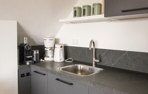 A modern kitchen with a stainless steel sink, a coffee maker, and a kettle. - Holiday apartment Mar by Lake Sneekermeer (Offingawier)