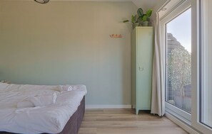 A bedroom with a bed, a tall cabinet, a window, and a view of buildings outside. - Holiday apartment Mar by Lake Sneekermeer (Offingawier)