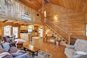 Une cabane en bois spacieuse, dotée d’une cuisine, d’un coin repas et d’un escalier menant à un niveau supérieur.