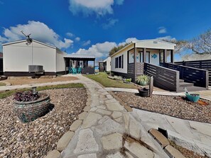 A caravan park with multiple caravans, a stone pathway, and a small fire pit. - Speckled Trout Cottages | Pet-Friendly + Canal Front (Rockport)