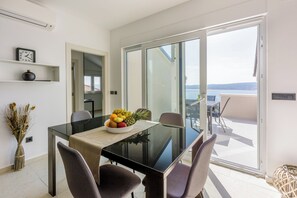 A modern dining area with a glass table, chairs, and a fruit bowl. - Large vacation apartment with 4 bedrooms, 4 bathrooms and swimming pool (Crikvenica)
