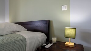 Ein Hotelzimmer mit einem Bett, einem Nachttisch mit Lampe, einer Fernbedienung und einer Kerze.