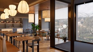 Un intérieur moderne avec des tables et des chaises en bois, ainsi que des luminaires suspendus.