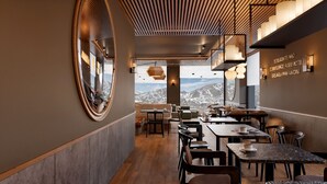 Un restaurant offrant une vue sur la montagne, doté d’un plafond en bois et d’un mobilier moderne.