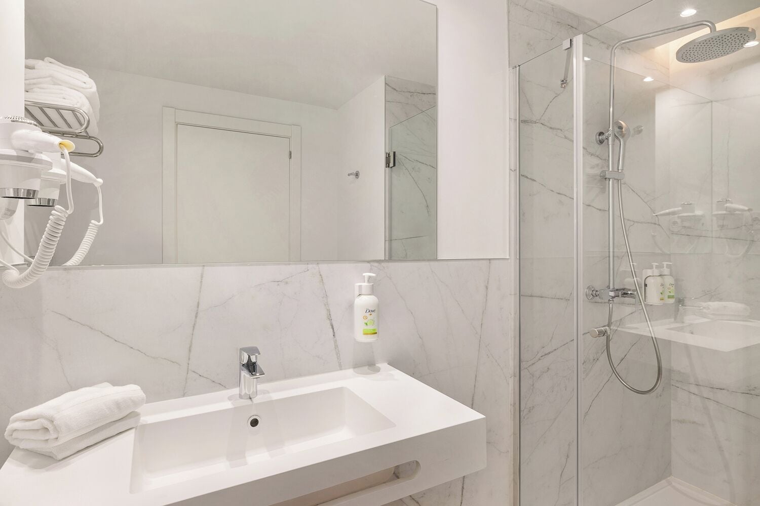 A modern bathroom with a white sink, a glass shower enclosure, and a towel rack.