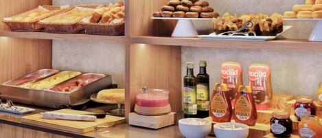 A buffet area with various food items, including bread, pastries, and condiments.