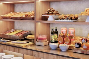 A buffet area with various food items, including bread, pastries, and condiments.