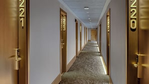 Pasillo de hotel con puertas numeradas del 221 al 225, piso alfombrado e iluminación empotrada en el techo.